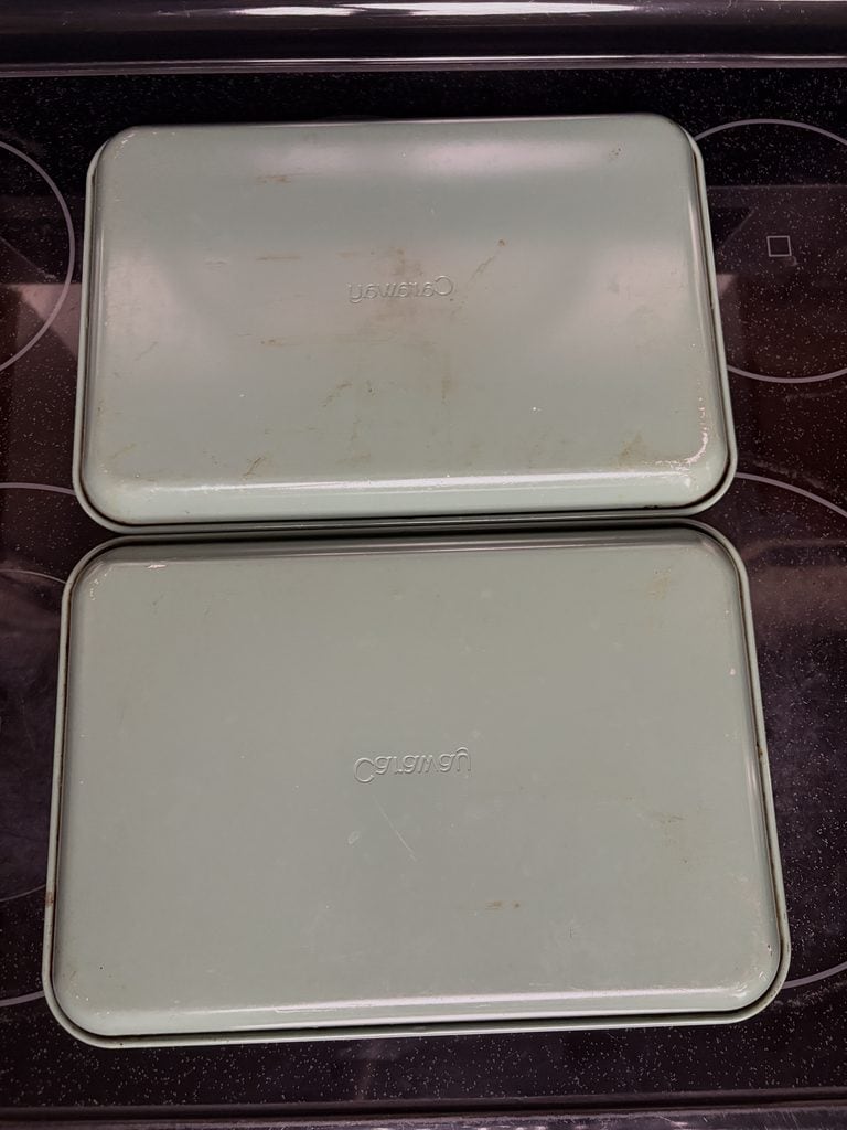 Green undersides of two Caraway baking sheets showing scratches, scuffs, and discoloration