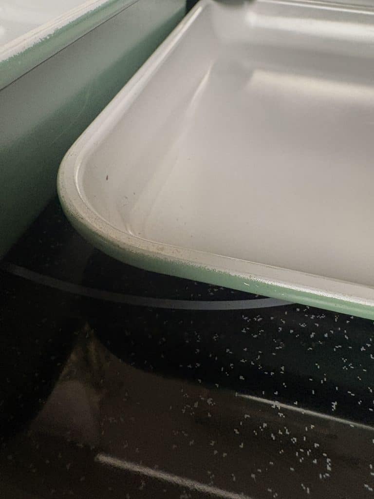 Close-up of a Caraway baking sheet’s rim showing wear along the edge and green exterior