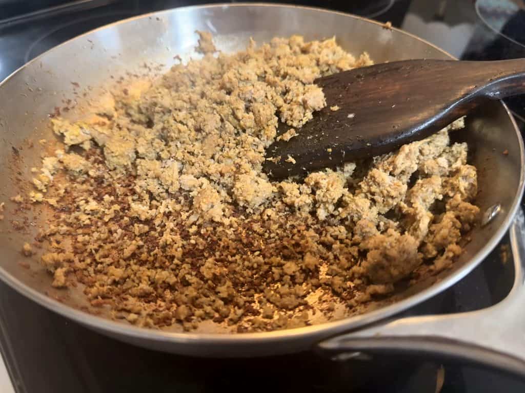 Ground turkey pushed aside with a wooden spoon, revealing browned residue in a Caraway stainless steel pan