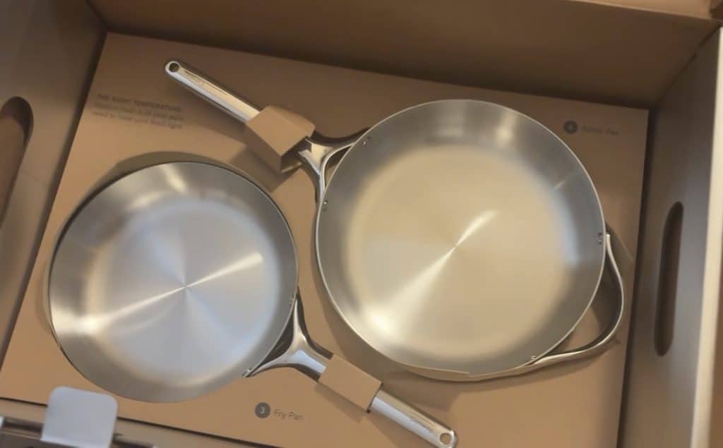 Caraway stainless steel frying pan and sauté pan nestled in their original cardboard packaging