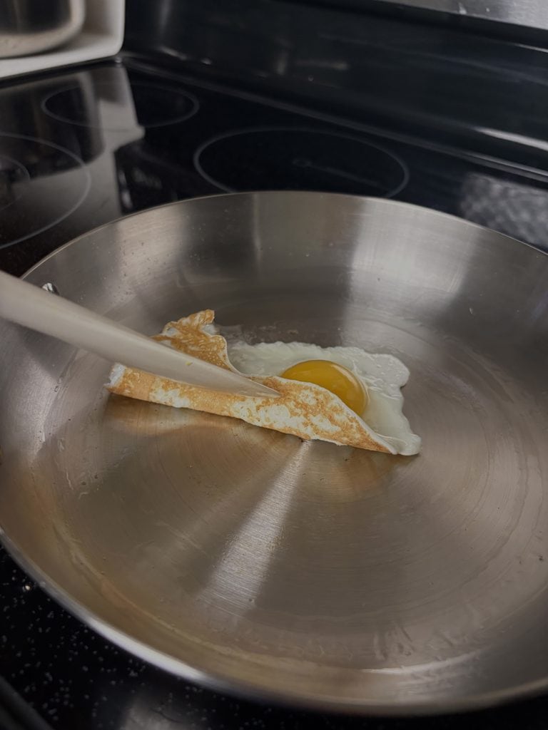 Spatula lifting the edge of a fried egg from our Caraway stainless steel pan