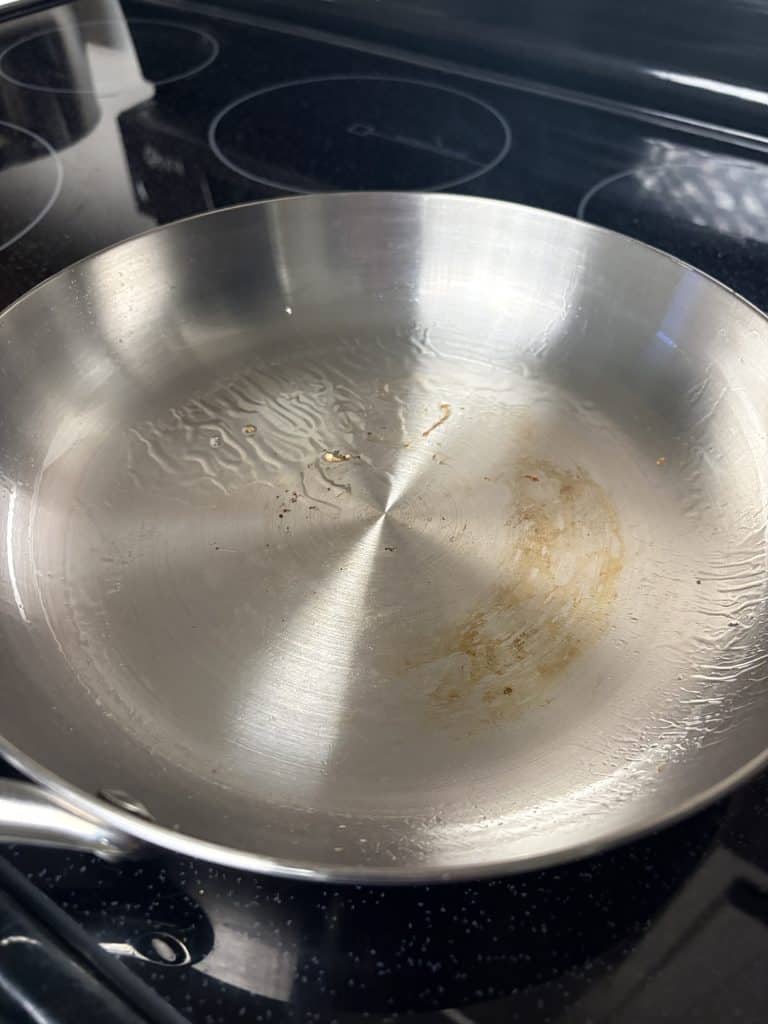 Small browned food remnants and oil left in our Caraway stainless steel pan after cooking an egg
